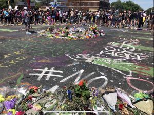 Image of George Floyd square with a memorial of flowers and people gathered